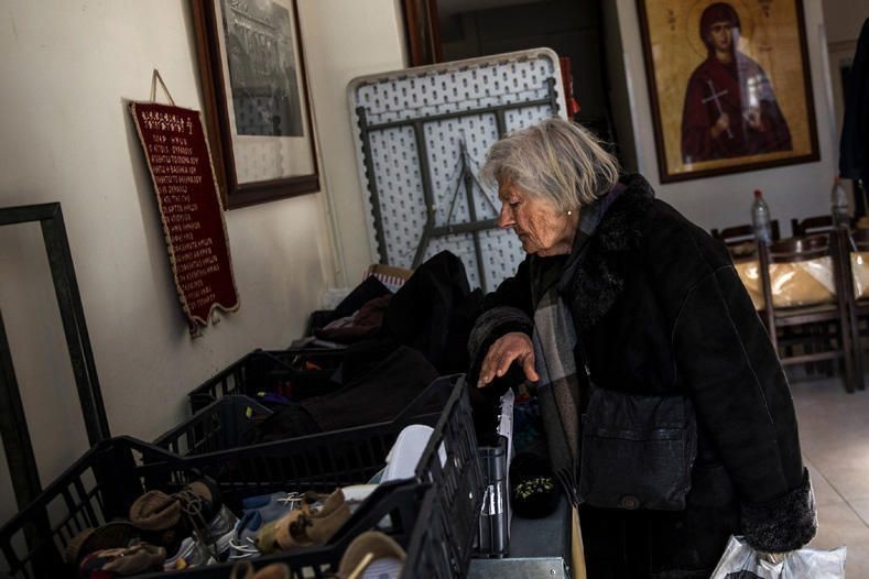 An elderly woman searches through donated clothes at a soup kitchen run by the Orthodox church in Athens, Greece, February 15, 2017. REUTERS/Alkis Konstantinidis