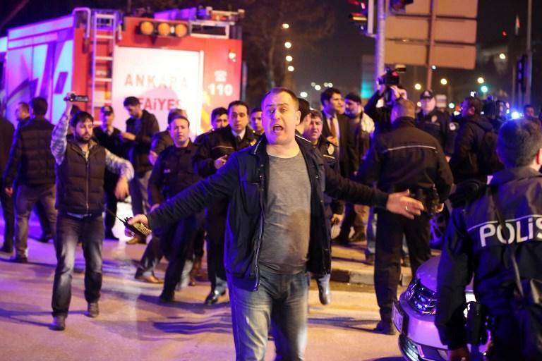 A man reacts next to policemen near the site of an explosion after an attack targeted a convoy of military service vehicles in Ankara on February 17, 2016. At least five people were killed and 10 people were wounded in a car bombing in the Turkish capital Ankara on February 17, the city's governor said. The attack targeted a convoy of military service vehicles, Ankara governor Mehmet Kiliclar said, quoted by the CNN-Turk and NTV channels. / AFP / EROL UCEM