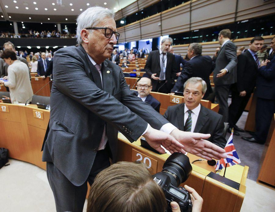 epa05395719 European Commission President Jean- Claude Juncker (L) tries to block a photographer's view on Nigel Farage (R), leader of the United Kingdom Independence Party (UKIP), prior to the start of a plenary session of the European Parliament, in Brussels, Belgium, 28 June 2016. The session will focus on the so-called 'Brexit' and is held ahead of a EU Summit. Later this afternoon EU leaders will met for the first time since the British referendum, in which 51.9 percent voted to leave the European Union (EU).  EPA/OLIVIER HOSLET