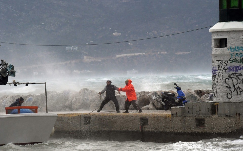 Δύο άνδρες παλεύουν με τους ισχυρούς ανέμους και τα πελώρια κύματα σε ένα λιμάνι