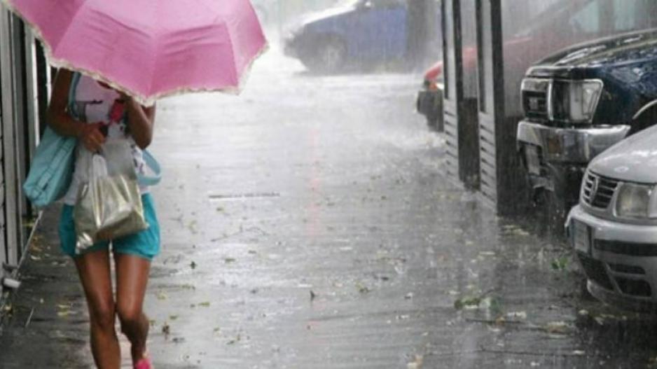 γυναίκα με ροζ ομπρέλα και σακούλες με ψώνια περπατά μέσα στη βροχή