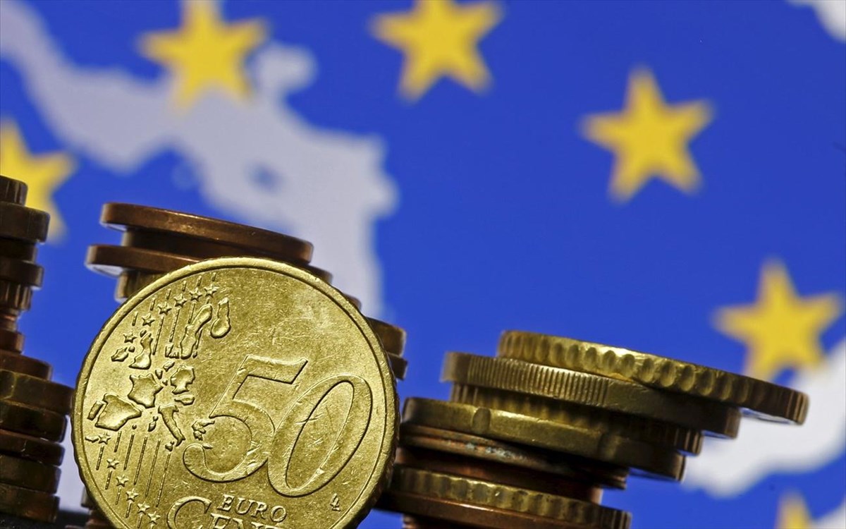 Νομίσματα του Ευρώ που χρησιμοποιούνται στις χώρες στην Ευρωζώνη μποστά από τη σημαία της ΕΕ