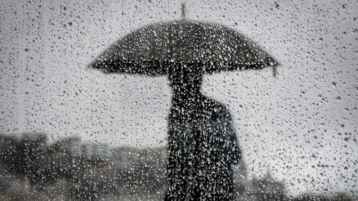 Μια ασπρόμαυρη φωτοραφία ενός ανθρώπου που κρατά ομπρέλα ενώ βρέχει