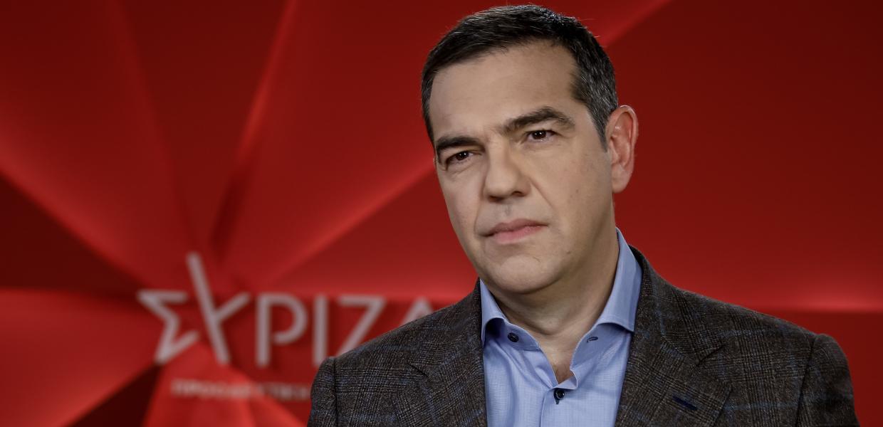 Ο πρόεδρος του ΣΥΡΙΖΑ Αλέξης Τσίπρας με κόκκινο φόντο με το λογότυπο του ΣΥΡΙΖΑ