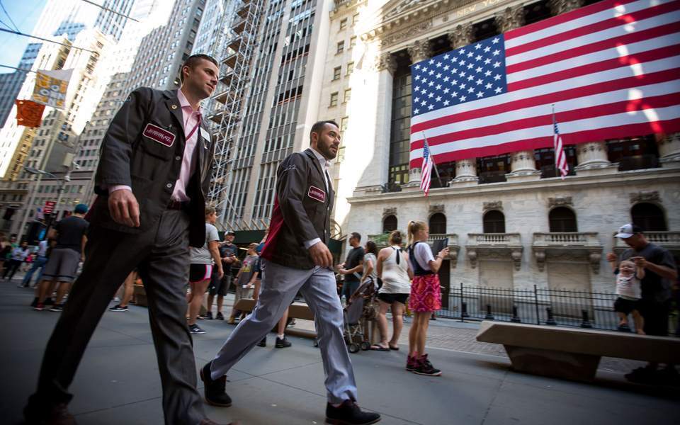 Δύο άνδρες περπατάνε έξω από το χρηματιστήριο της Νέας Υόρκης στη Wall Street