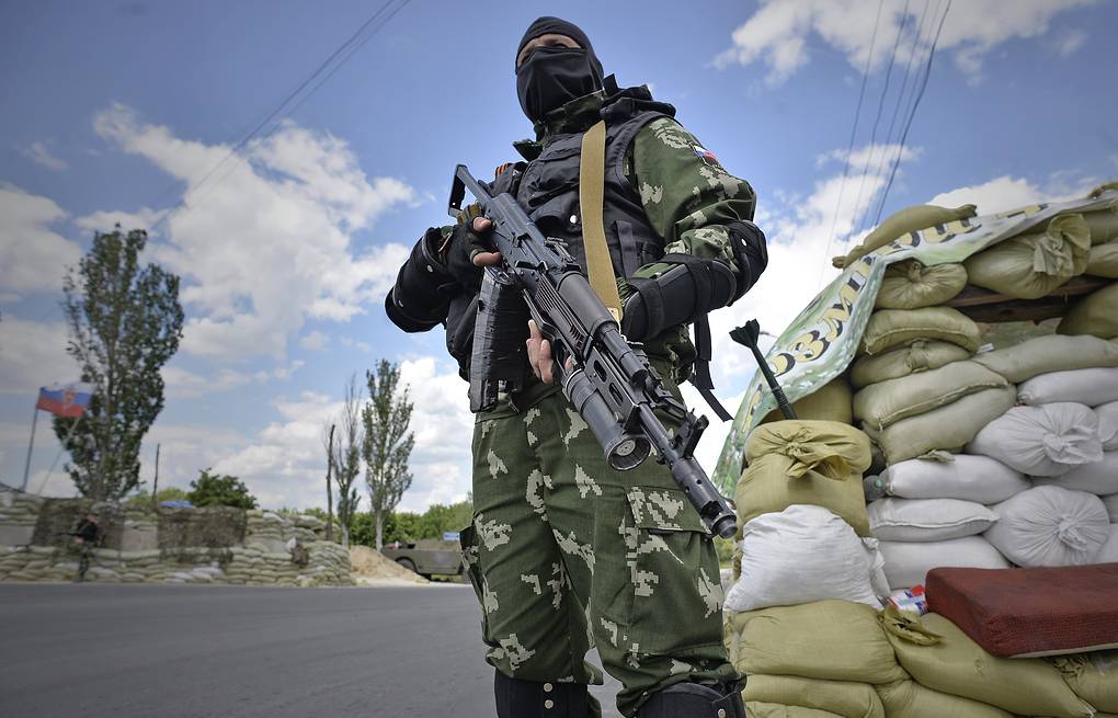 στρατιώτης αυτονομιστών στο Ντόνετσκ με στολή παραλλαγής και όπλο στα χέρια, μπροστά σε οδόφραγμα