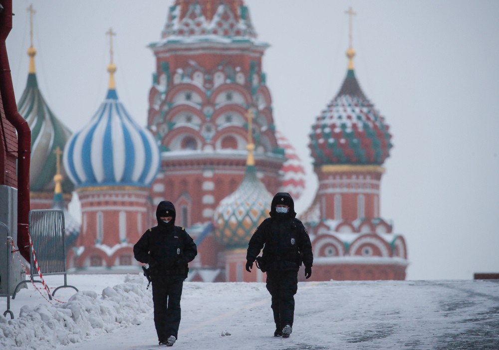 Άνθρωποι στην χιονισμένη κόκκινη πλατεία στη Μόσχα μπροστά από τον ναό του Αγίου Βασιλείου