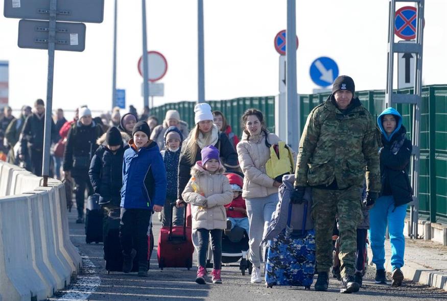ουκρανοί πρόσφυγες, μεταξύ των οποίων και παιδιά, κινούνται δίπλα σε δρόμο