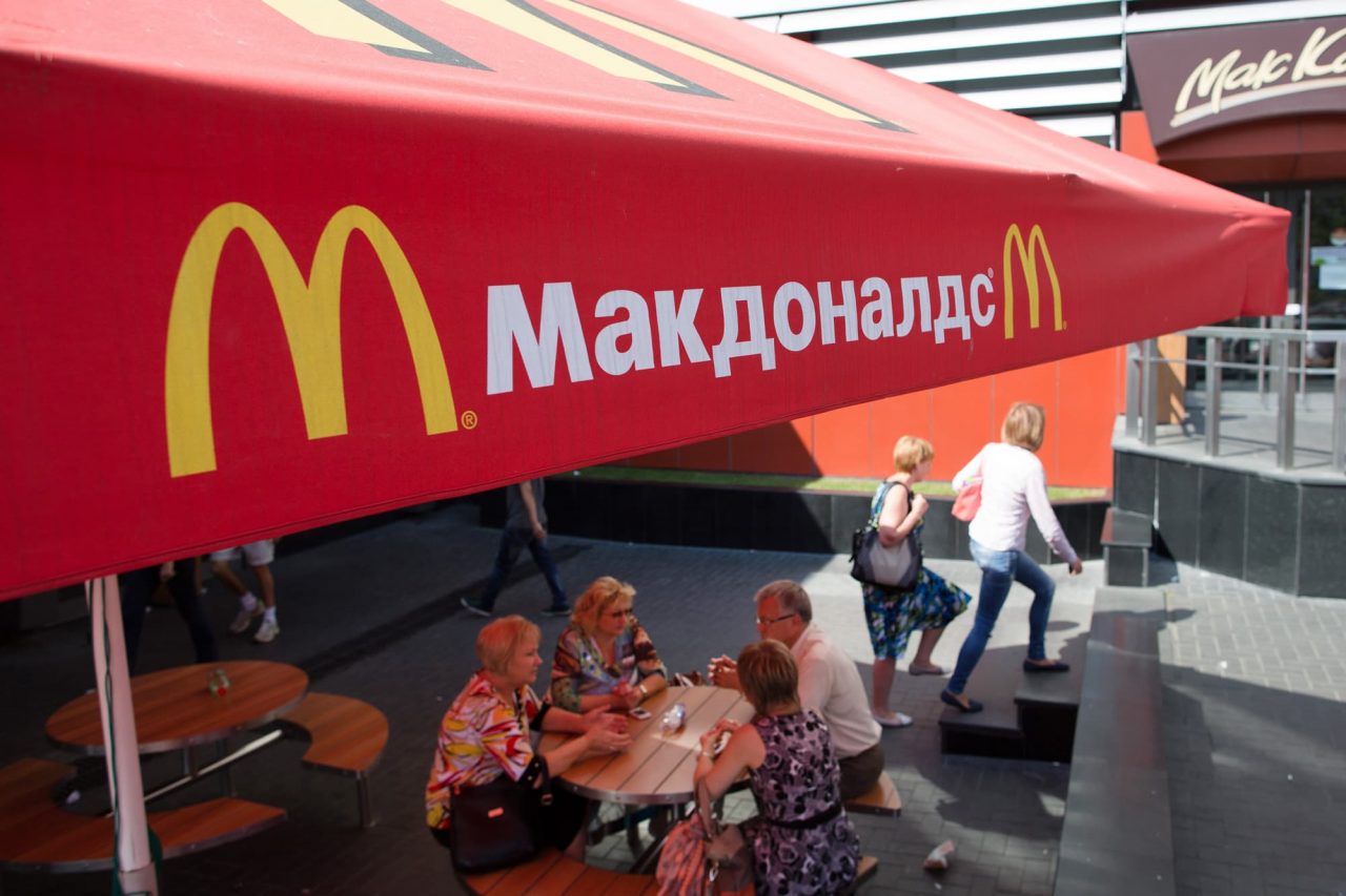 άνθρωποι στη Ρωσία τρώνε σε κατάστημα McDonald’s κάτω από στέγαστρο με το σήμα της