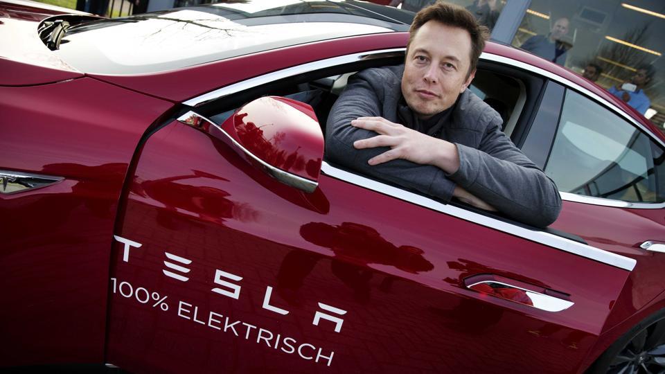 Ο Elon Musk, συνιδρυτής και διευθύνων σύμβουλος της Tesla, ποζάρει σε ένα μοντέλο της εταιρείας κατά τη διάρκεια μιας επίσκεψης στο Άμστερνταμ.