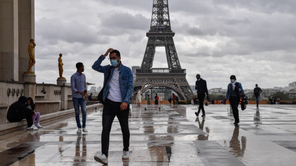 Άνθρωποι με μάσκες περπατούν γύρω από τον Πύργο του Άιφελ