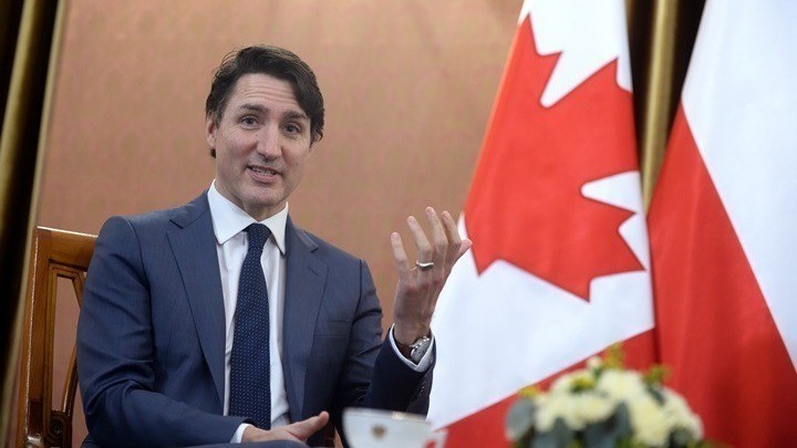 Ο Τζαστίν Τριντό μιλά δίπλα από μια σημαία του Καναδά