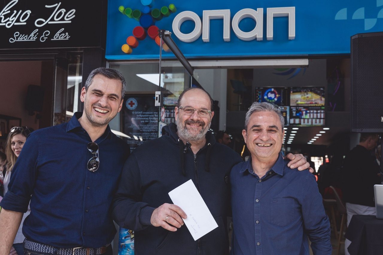 Ο Chief Retail Officer του ΟΠΑΠ, Ηλίας Κατσαρός, με τον νικητή της κλήρωσης και τον ΟΠΑΠ Stores Director, Βαγγέλη Γκεβέζο