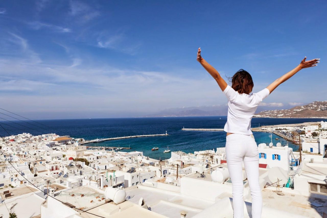 Γυναίκα απολαμβάνει τη θέα σε νησί της Ελλάδας - WTTC: Ο παγκόσμιος τουρισμός θα ανακάμψει από την πανδημία έως το 2023