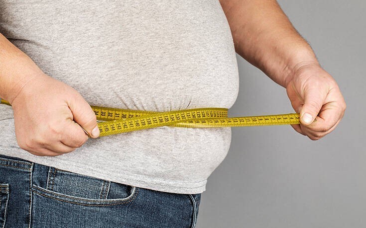 Άνθρωπος μετράει την κοιλιά του με μεζούρα και πάσχει από παχυσαρκία