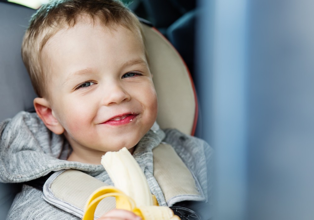 Παιδάκι τρώει μπανάνα για σνακ κατά τη διάρκεια ταξιδιού