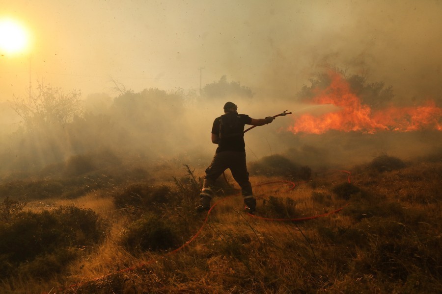 Πυροσβέστης επιχειρεί σε φωτιά που βρίσκεται σε εξέλιξη στο Νταού Πεντέλης