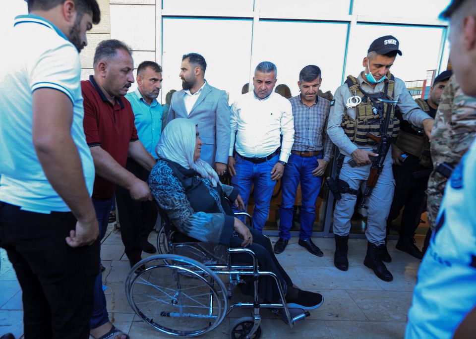 A man pushes a wheelchair carrying a woman wounded by a Turkish attack, next to a hospital in Zakho