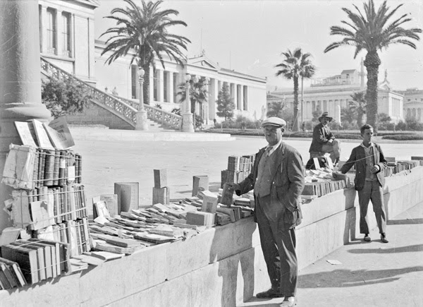 Πλανόδιος έμπορος βιβλίων μπροστά την Βιβλιοθήκη και την τριλογία