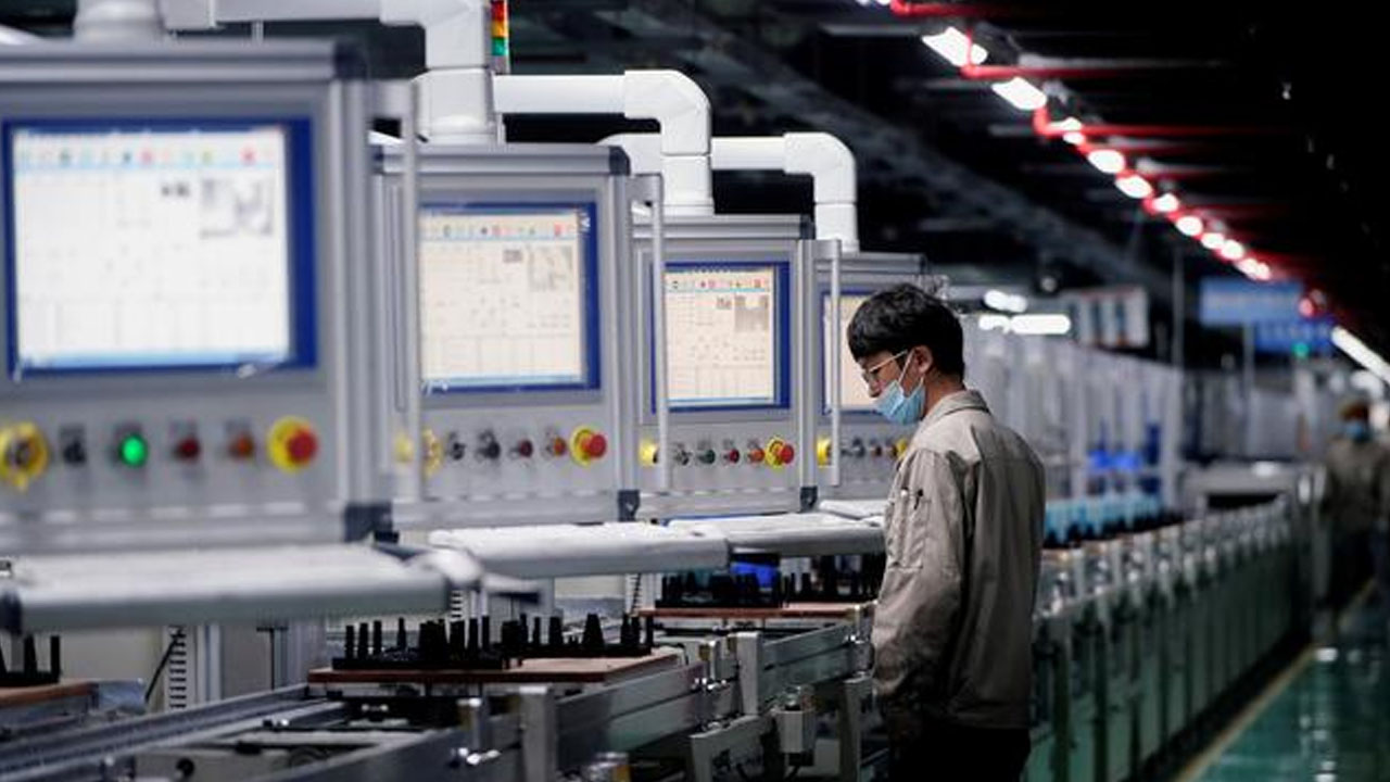Εργάτης με μάσκα σε γραμμή παραγωγής ηλεκτρικών οχημάτων σε εργοστάσιο στην Κίνα