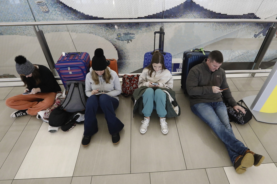 Επιβάτες περιμένουν στο πάτωμα στο terminal B στο αεροδρόμιο της Νέας Υόρκης λόγω ακυρώσεων και καθυστερήσεων πτήσεων που προκάλεσε η σφοδρή κακοκαιρία που πλήττει τις ΗΠΑ