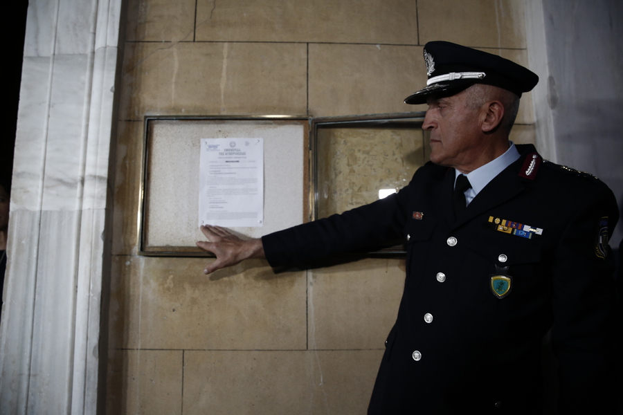 Αστυνομικός θυροκολλεί στην είσοδο της Βουλής το Προεδρικό Διάταγμα για τη διάλυσή της