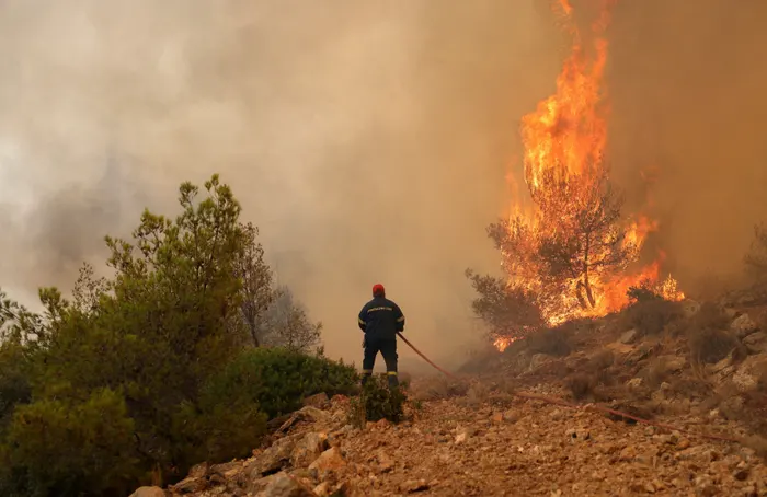 Πυροσβέστης προσπαθεί να σβήσει την πυρκαγιά που καίει κοντά στο Κανδήλι, κοντά στην Αθήνα. Φωτογραφία: Στέλιος Μισίνας/Reuters