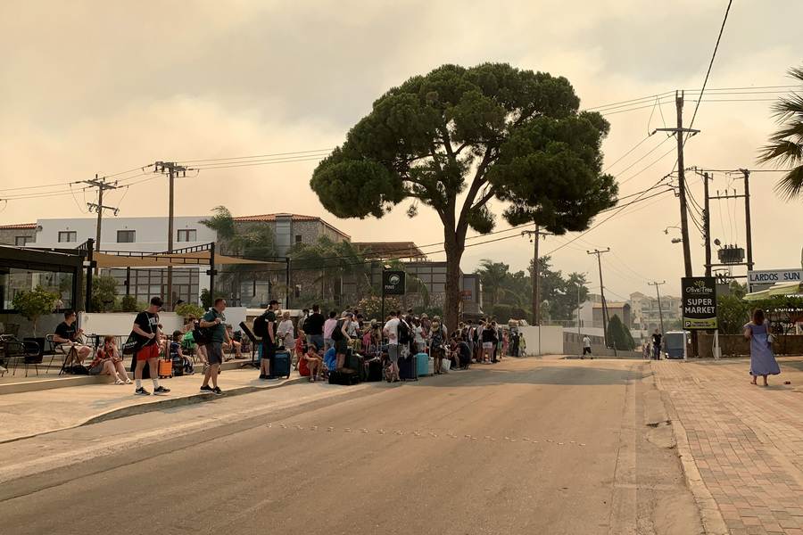 Τουρίστες περιμένουν να μεταφερθούν σε ασφαλές μέρος κατά την διάρκεια εκκένωσης στην περιοχή Πεύκοι νότια της Ρόδου