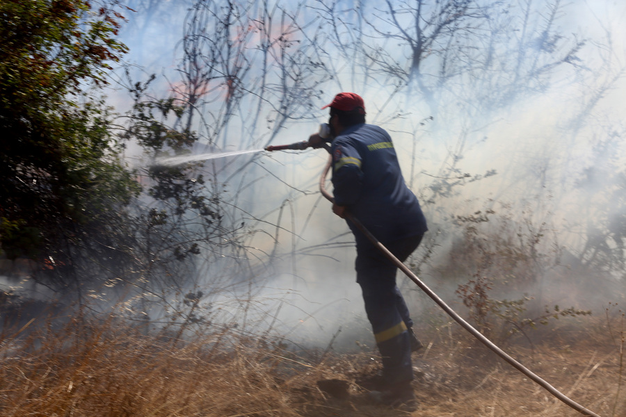 Πυροσβέστης ρίχνει νερό κατά την διάρκεια κατάσβεσης της φωτιάς στο χωριό Λουτρός στην Αλεξανδρούπολη