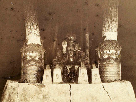 Προγονικό ιερό στο βασιλικό παλάτι του Μπενίν το 1891 με δύο χάλκινα κεφάλια στα άκρα. Η παλαιότερη γνωστή φωτογραφία του βασιλικού συγκροτήματος