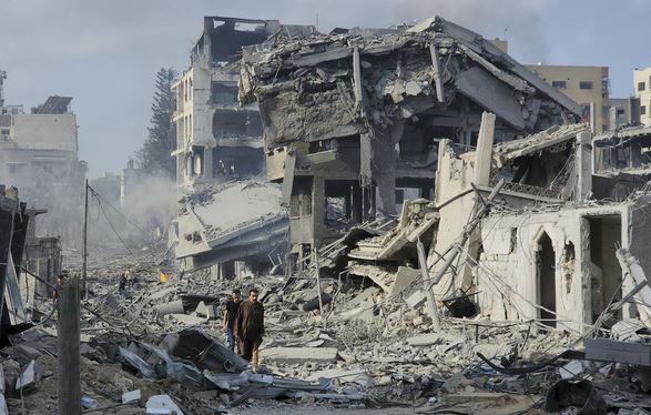 Παλαιστίνιοι περπατούν μέσα από τα ερείπια κτιρίων που καταστράφηκαν από τις ισραηλινές αεροπορικές επιδρομές στην πόλη της Γάζας την Τρίτη, 10 Οκτωβρίου 2023.