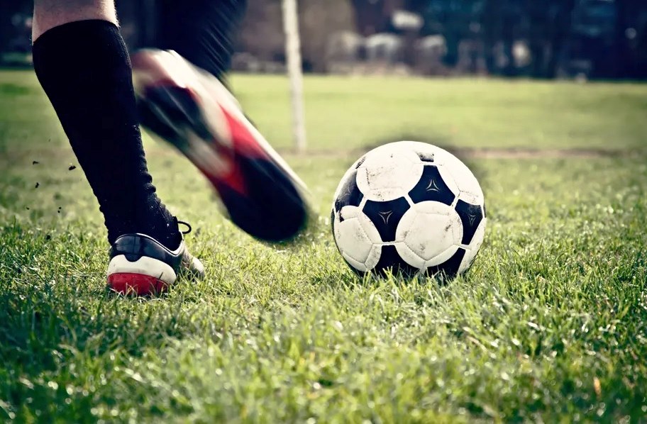 Ποδοσφαιριστής σουτάρει μπάλα σε γήπεδο ποδοσφαίρου