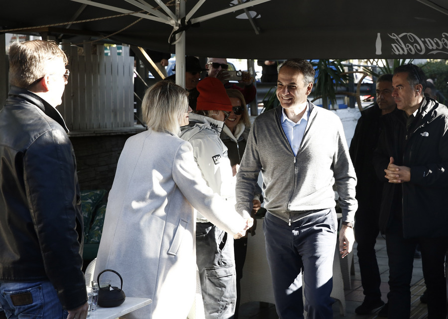 Ο πρωθυπουργός Κυριάκος Μητσοτάκης χαιρετάει πολίτες κατά τη διάρκεια της επίσκεψής του σε καφετέρια στο Πέραμα