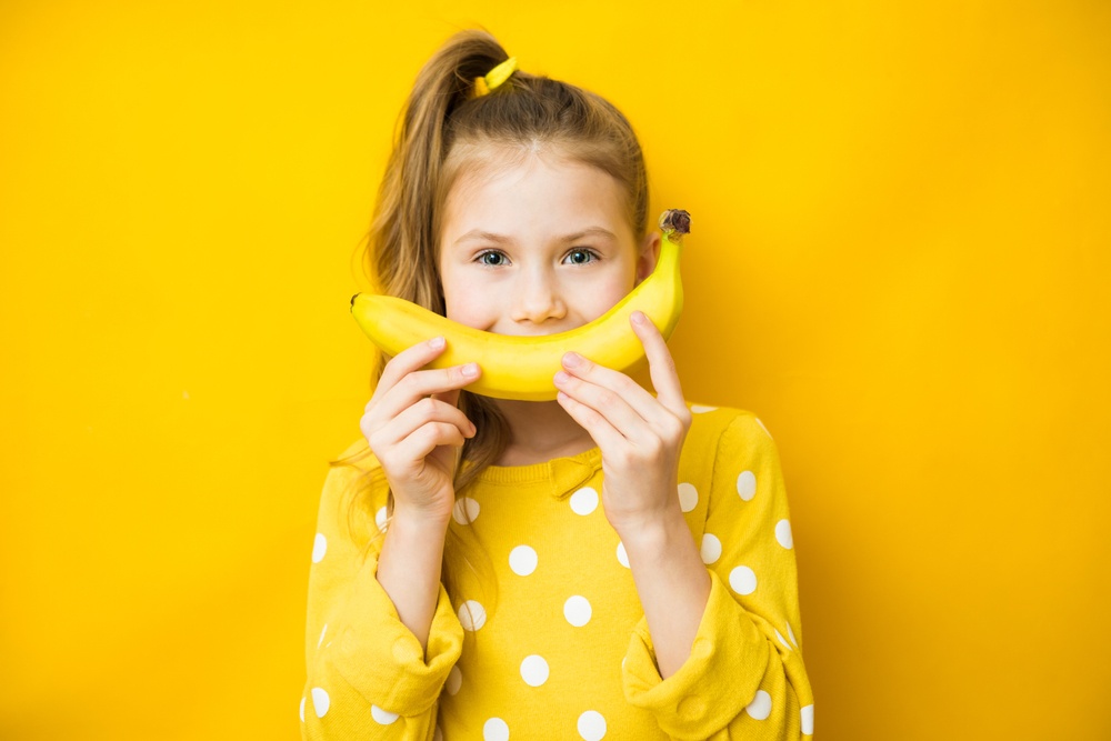 Παιδί κρατάει μία μπανάνα προκειμένου να εντάξει τα φρούτα στη διατροφή του