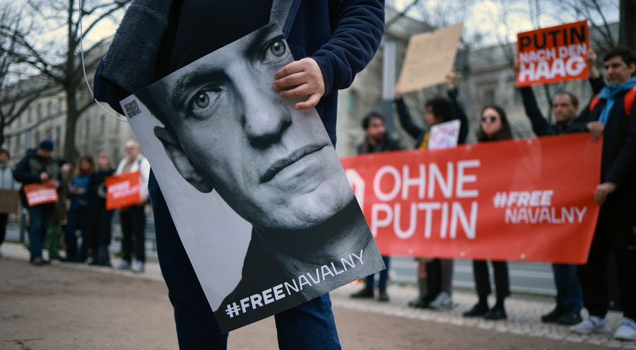 Διαδηλωτές για τον θάνατο του Αλεξέι Ναβάλνι έξω από την πρεσβεία της Ρωσίας στο Βερολίνο κρατούν πανώ κατά του Πουτιν και εικόνες του Αλεξέι Ναβάλνι