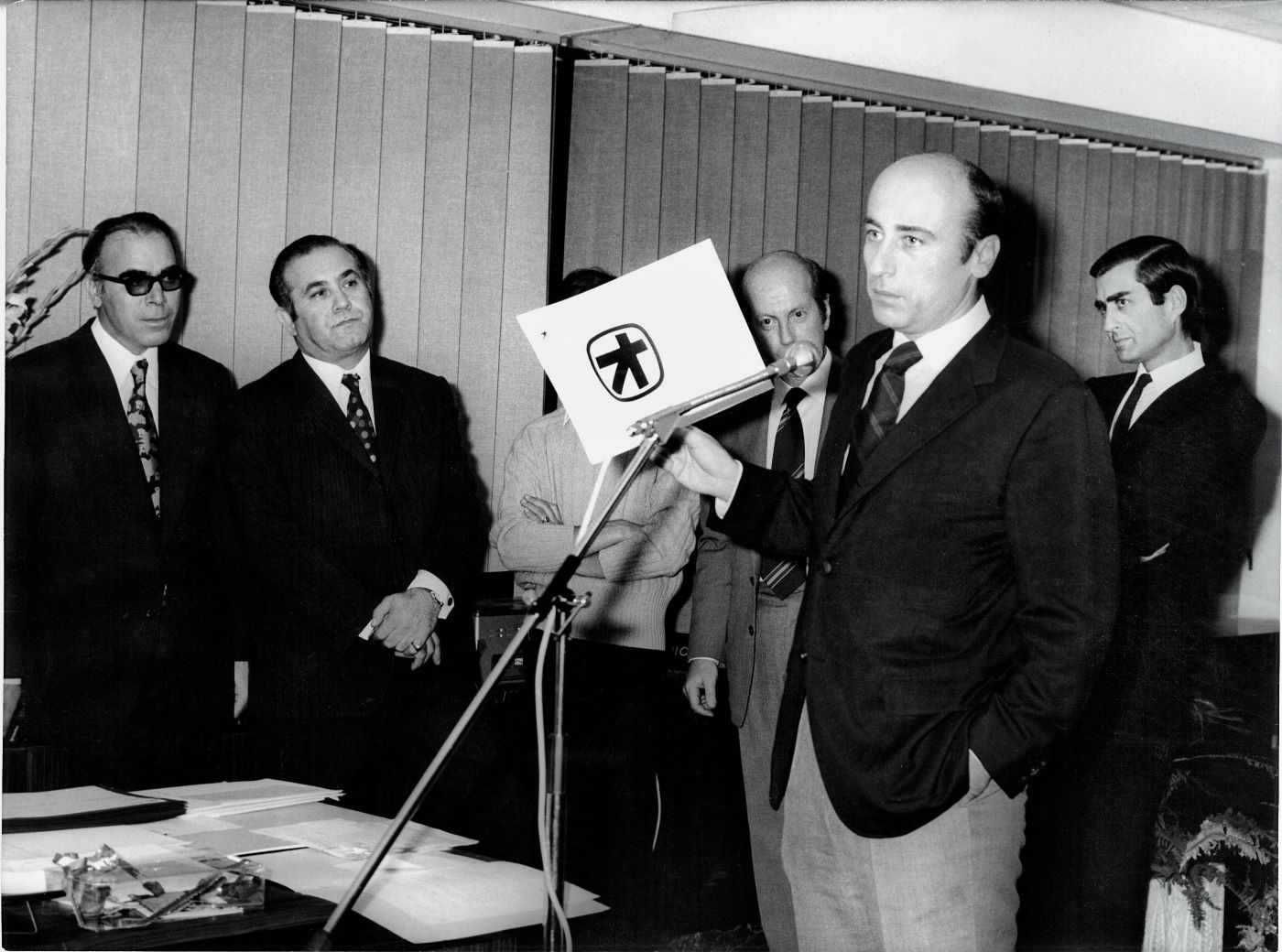 Ο Γιάννης Κωστόπουλος, παρουσιάζει το νέο σήμα της Τράπεζας Πίστεως, 1972