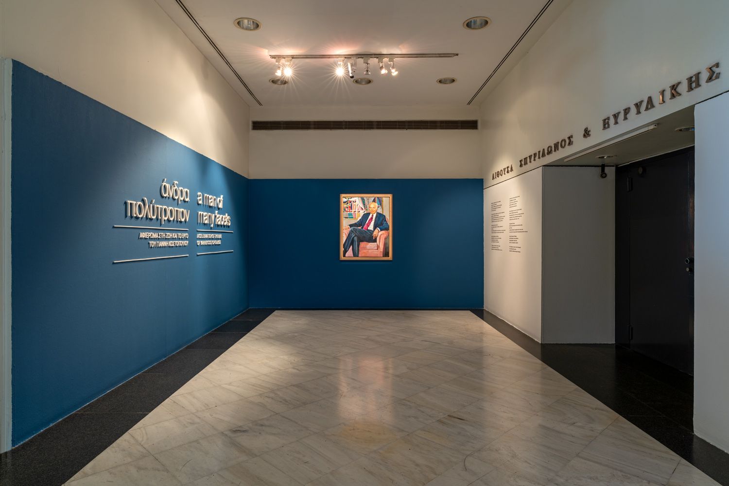 Το πορτρέτο το Γιάννη Κωστόπουλου στην είσοδο της αίθουσας περιοδικών εκθέσεων Σπυρίδωνος και Ευρυδίκης Κωστοπούλου στο Μουσείο Μπενάκη
