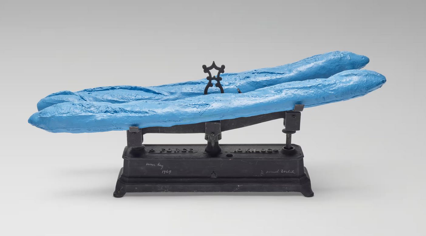 Γλυπτό του Μαν Ρέι με δύο μπλε μπαγκέτες που στηρίζονται σε παλιά σιδερένια ζυγαριά