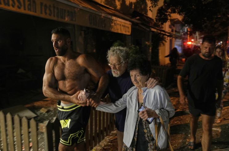 Άνθρωποι στους δρόμους μετά την εκτόξευση πυραύλου από το Ιράν που έπληξε το Τελ Αβίβ, Ισραήλ, Δευτέρα 16 Ιουνίου 2025. (AP Photo/Baz Ratner)