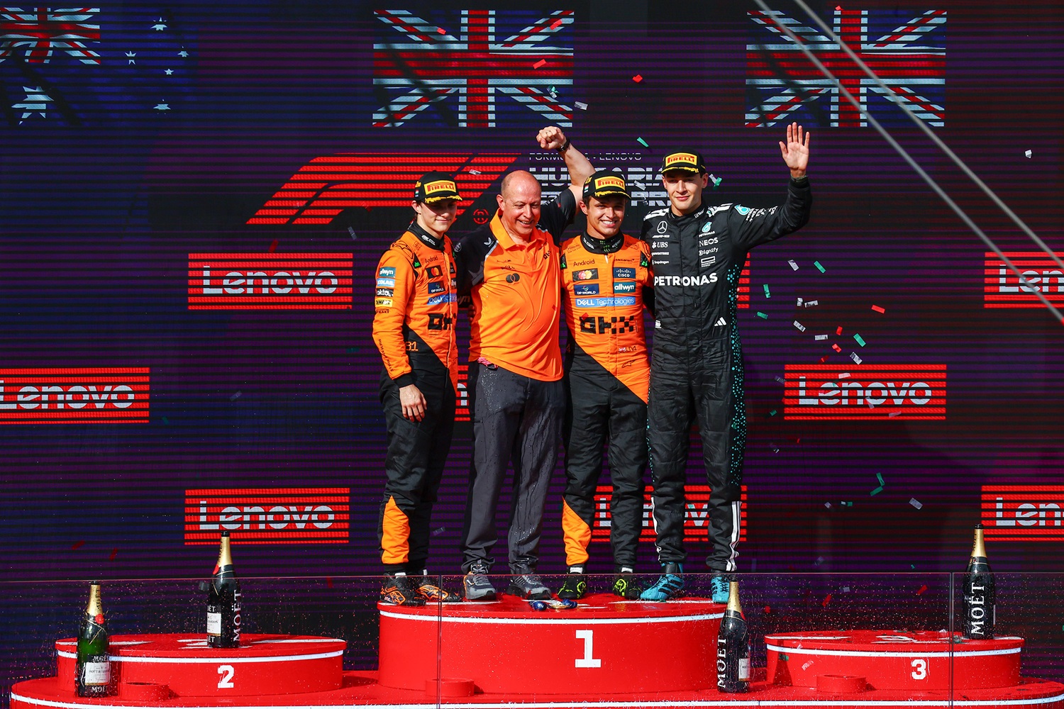 O Lando Norris, o Oscar Piastri και ο George Russell, μαζι με τον Mark Ingham, Head of Design της McLaren στο βάθρο των νικητών