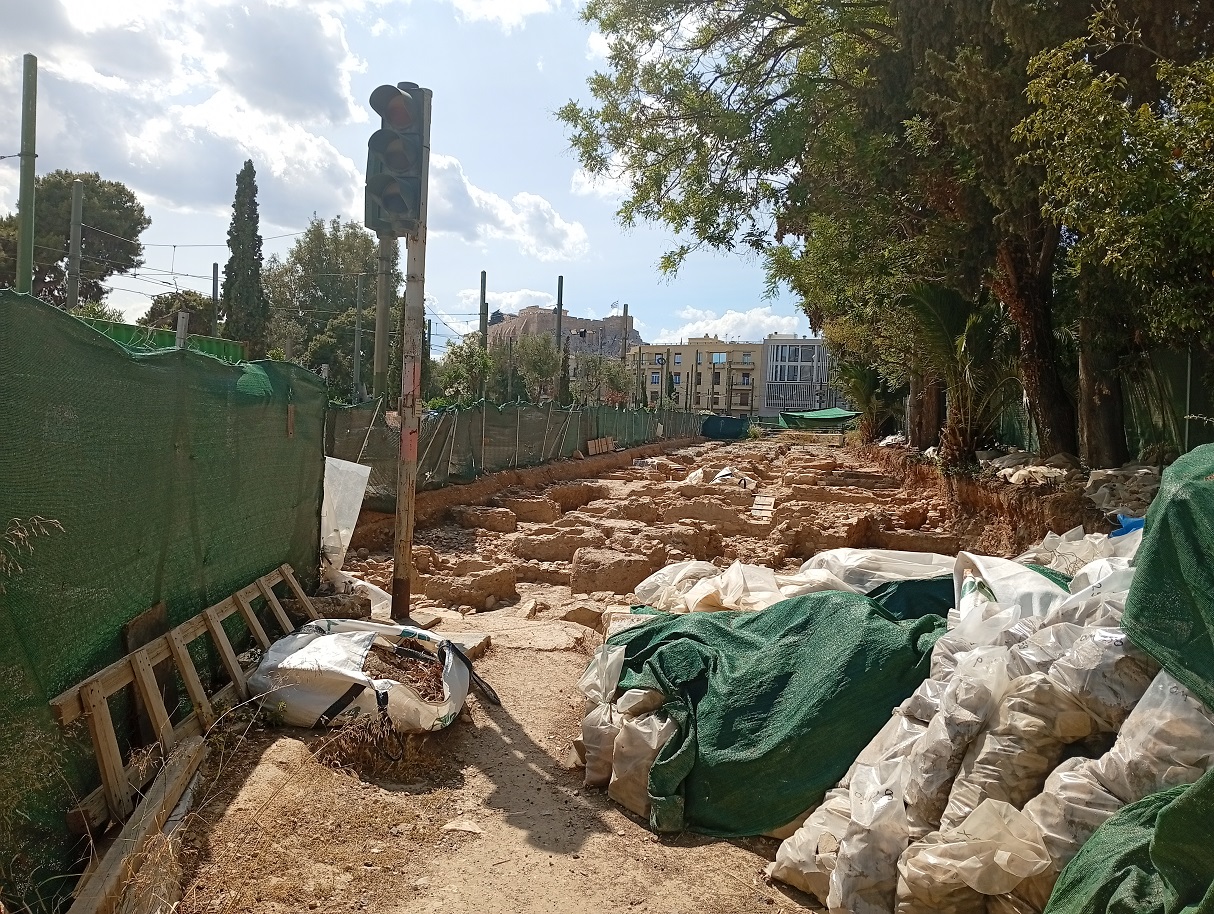 Άποψη των αρχαιολογικών ευρημάτων στη Βασιλίσσης Όλγας, προστατευμένα με ειδική περίφραξη, μη προσβάσιμα από το κοινό. Πηγή φωτογραφίας: mononews.gr, Iούλιος 2025
