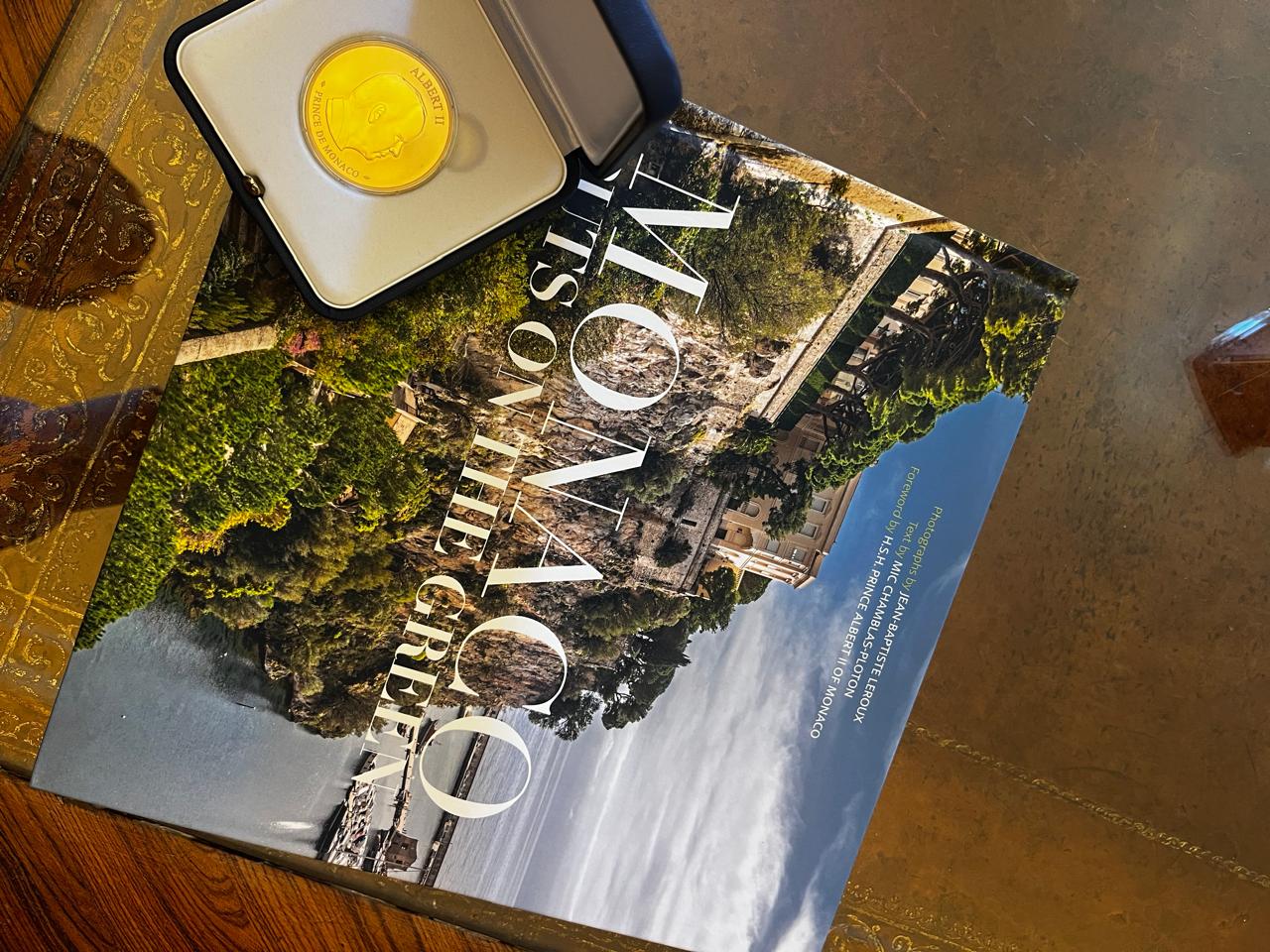 Τα δύο δώρα του Πρίγκιπα Αλβέρτου στον Κωνσταντίνο Τασούλα, ένα συλλεκτικό χρυσό νόμισμα του 2006, αναμνηστικό της δημιουργίας του «Ιδρύματος Πρίγκιπας Αλβέρτος» και ένα λεύκωμα με φωτογραφίες των Κήπων του Πριγκιπάτου.