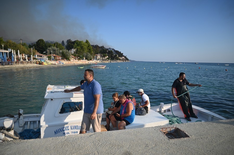 Κόσμος απομακρύνεται με πλωτά μέσα από την παραλία της Σίβηρης, κατά τη διάρκεια της φωτιάς που ξέσπασε στη Σίβηρη Χαλκιδικής, (ΑΠΕ-ΜΠΕ)
