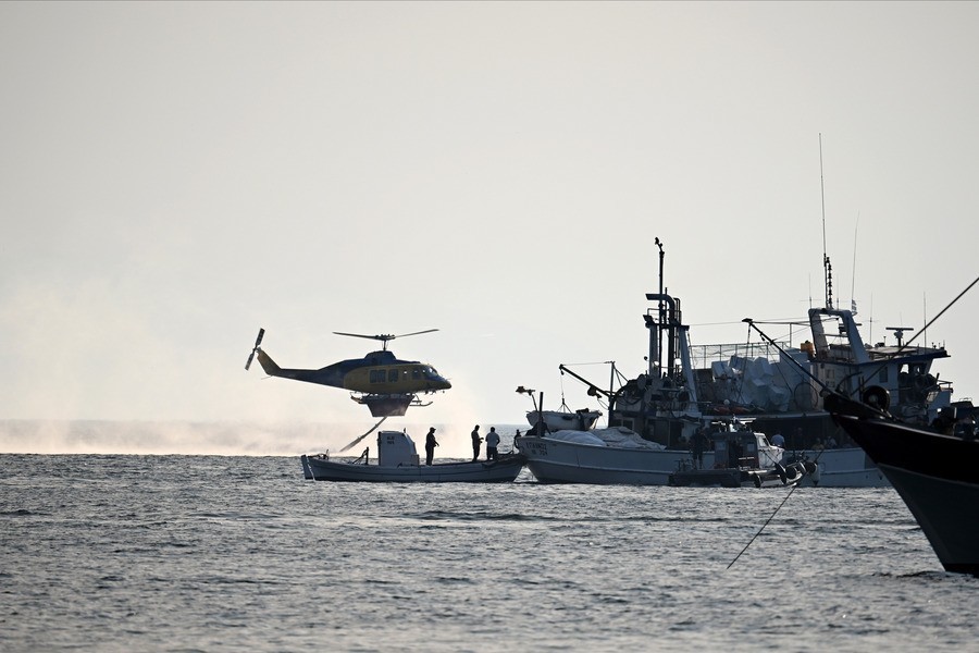 Κόσμος απομακρύνεται με πλωτά μέσα από την παραλία της Σίβηρης, κατά τη διάρκεια της φωτιάς που ξέσπασε στη Σίβηρη Χαλκιδικής, (ΑΠΕ-ΜΠΕ)